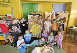 dzieci pozują do zdjęcia grupowego prezentując swoją pracę
