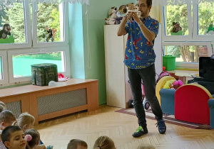 Dzieci siedzą na dywanie słuchając muzyki