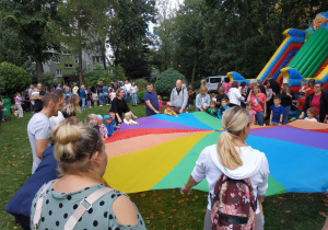 Dzieci i i rodzice biorą udział we wspólnych zabawach z chustą animacyjną