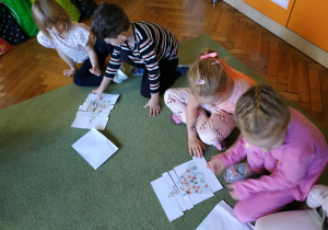 Dzieci siedzą na dywanie, układają piramidę zdrowego żywienia