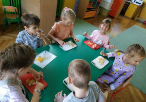 dzieci siedzą przy stolikach, kroją owoce i warzywa potrzebne do zrobienia koktajlu