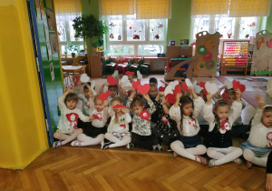 Dzieci siedzą na dywanie, śpiewają piosenki patriotyczne oraz pokazują serca białe i czerwone podczas utworu