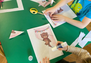Dzieci przy stoliki wycinają i układają puzzle „Miś”