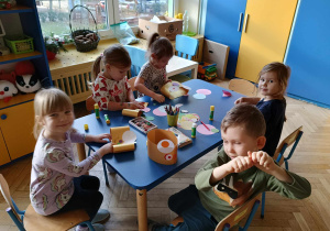 dzieci siedzą przy stoliku, wykonują misiowe opaski z kół origami