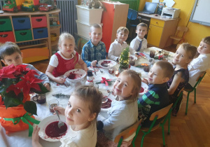 Dzieci siedzą przy stole, spożywają posiłek
