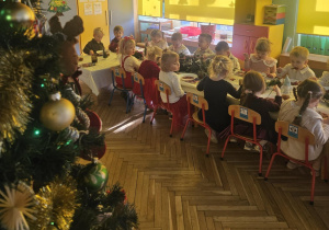 Dzieci siedzą przy stole, spożywają posiłek