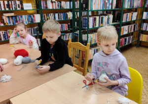 dzieci zwijają wełnę robiąc pompony