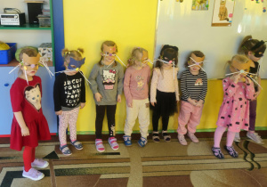 Dzieci w maskach kotka bawią się na dywanie