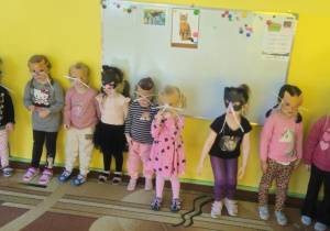Dzieci w maskach kotka bawią się na dywanie