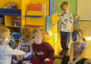 Dzieci w maskach kotka bawią się na dywanie
