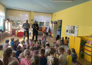 dzieci siedzą na dywanie, słuchają audycji muzycznej