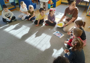dzieci wraz z Panią Kamilą siedzą w kole na dywanie