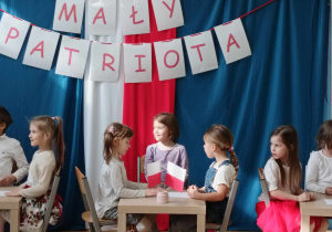 dzieci siedzą przy stolikach podczas quizu patriotycznego