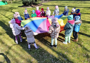 Dzieci bawią się z chusta animacyjną w ogrodzie przedszkolnym