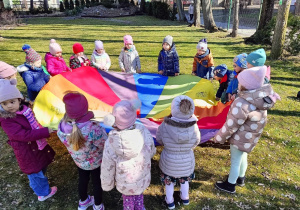 Dzieci bawią się z chusta animacyjną w ogrodzie przedszkolnym