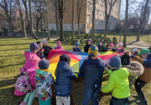 Dzieci bawią się z chusta animacyjną w ogrodzie przedszkolnym