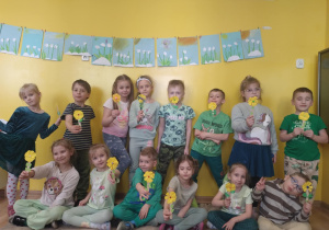 dzieci trzymają w ręku kwiatki i pozują do zdjęcia grupowego