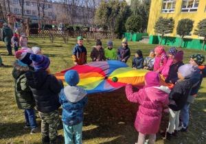 Dzieci bawią się z chusta animacyjną w ogrodzie przedszkolnym