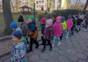 Dzieci maszerują korowodem wokół przedszkola, witając wiosnę