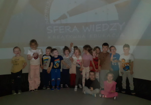dzieci pozują do zdjęcia grupowego w środku mobilnego planetarium