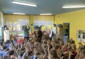 dzieci tańczą na dywanie, słuchając muzyka który gra na saksofonie.