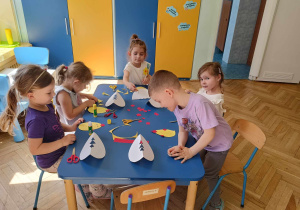dzieci siedzą przy stoliku, wykonują kurczęta wykluwające się ze skorupek