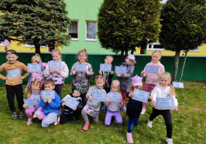dzieci pozują do zdjęcia grupowego, w ręku trzymają dyplom