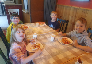 Dzieci jedzą przygotowane przez siebie pizzę