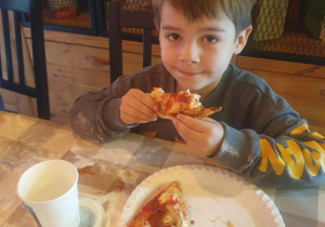 chłopiec je przygotowaną przez siebie pizzę