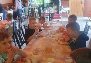 Dzieci jedzą przygotowane przez siebie pizze