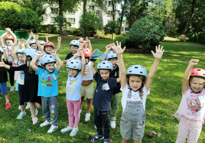 Dzieci z kaskami na głowie stoją w ogrodzie przedszkolnym