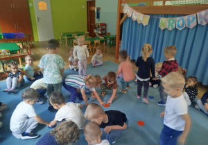 Dzieci biorą udział w zabawie ruchowej, omijając kolorowe kropki