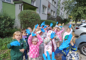 Dzieci stojące przy bloku z założonymi rękawiczkami rozpoczynające akcje sprzątanie Świata