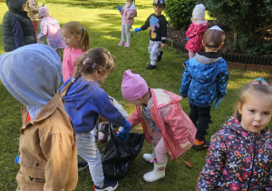 dzieci sprzątają śmieci i wrzucają je do worka