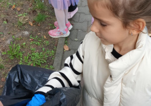 dziewczynka wrzuca śmieci do worka