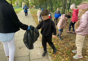 chłopiec wrzuca śmieci do worka