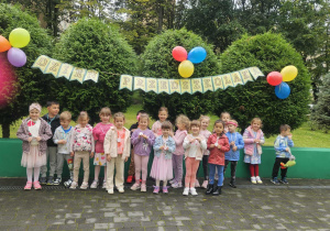 Dzieci stoją na tarasie przedszkolnym, pozują do zdjęcia grupowego