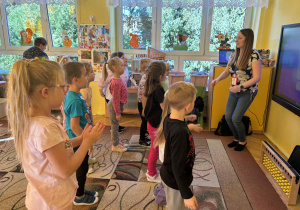 prowadząca objaśnia dzieciom wykonanie zadania na monitorze edukacyjnym