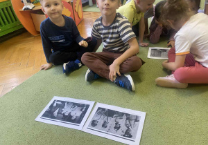 dzieci siedzą na dywanie oglądając zdjęcia