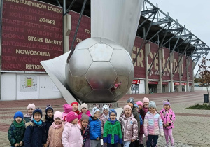 dzieci stoją przy pomniku Widzewa, pozują do zdjęcia