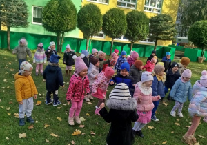 Dzieci w ogrodzie ustawione w rozsypce ćwiczą chwyt karate