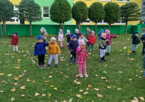 Dzieci w ogrodzie ustawione w rozsypce ćwiczą chwyt karate