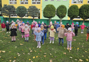 Dzieci w ogrodzie ustawione w rozsypce ćwiczą chwyt karate