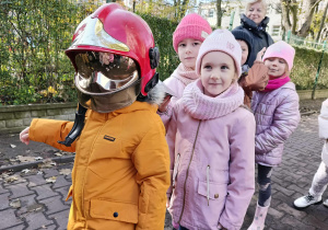 Dzieci przymierzają kaski strażackie.