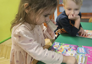 Dziewczynka wyszukuje elementów obrazka za pomocą lornetki z rolki.