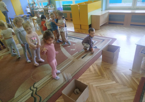 Dzieci rzucają kule z gazet do tekturowych kartonów