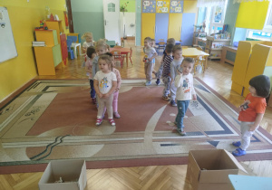 Dzieci rzucają kule z gazet do tekturowych kartonów