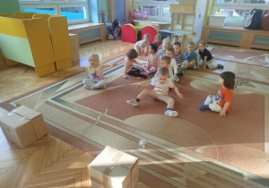 Dzieci w drużynach turlają kule z gazet do tekturowych pudelek