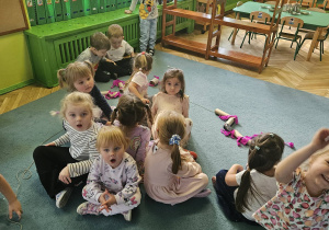 Dzieci w kole przeciągają rolki po sznurku