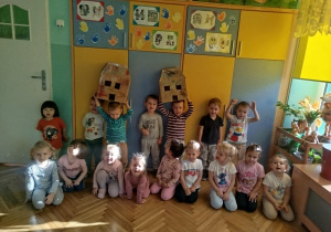 Dzieci z grupy pomarańczowej pozują do zdjęcia grupowego z wykonanymi przez siebie domkami
